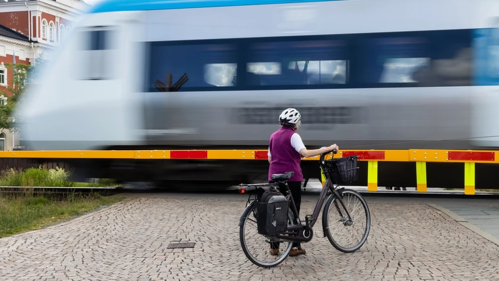 Kvinna med cykel vid järnvägsövergång vid hamnen den 15 juni 2022 i Jönköping. Genre Sverige Makro inflation BNP 